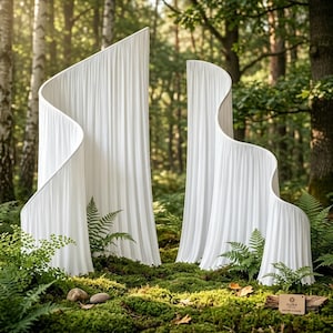 May include: Two white, tall, curved room dividers with a vertical pleated texture. The structures feature smooth, undulating edges and a clean, solid white finish. A small rectangular wooden tag with the text AURA NATURE & SHAPE is visible.