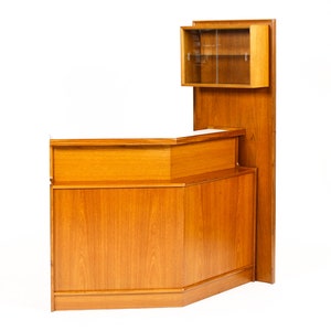 May include: A mid-century modern teak bar unit with a glass-front cabinet on top. The bar unit has a curved front and a wood grain finish.