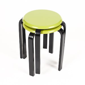 May include: Two green wooden stools with black legs stacked on top of each other.