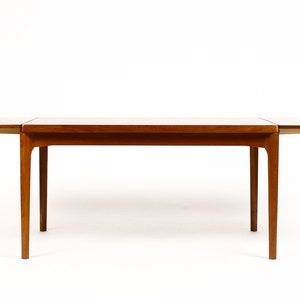 May include: A wooden extendable dining table with a light brown finish. The table has a rectangular top and four legs. The table is shown with the leaves extended.