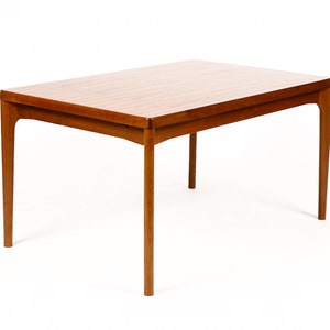 May include: A rectangular wooden dining table with a light brown finish and four legs. The table has a simple, mid-century modern design.