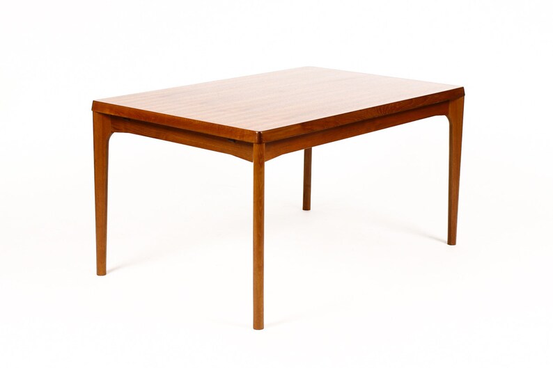 May include: A rectangular wooden dining table with a light brown finish and four legs. The table has a simple, mid-century modern design.