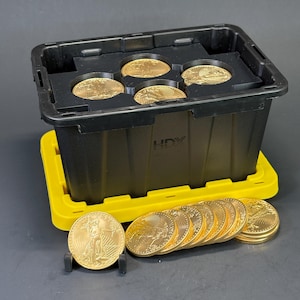 May include: A black plastic storage bin with a yellow lid featuring the HDX logo, containing five gold coins in circular slots. A row of ten gold coins stands upright in front of the bin, with one coin displayed on a small black plastic stand.