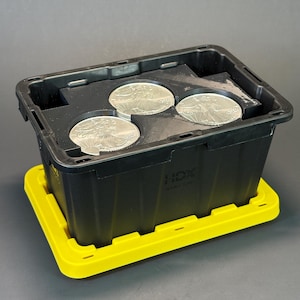 May include: A black plastic storage bin with a yellow lid base, featuring the text HDX embossed on the side. Inside the bin, a black foam insert holds three round silver coins, each displaying a detailed embossed figure of a person in motion.