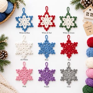 May include: A collection of nine crocheted snowflake ornaments arranged in a grid. The snowflakes feature various color combinations including white and blue, white and red, white and green, all white, solid blue, red, pink, purple, and gray.