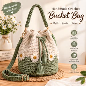 Puede incluir: Un bolso tipo cubo de ganchillo hecho a mano con una base verde salvia y una parte superior color crema. El bolso está decorado con motivos de margaritas blancas con centros amarillos e incluye un cierre de cordón verde salvia con borlas y correa.