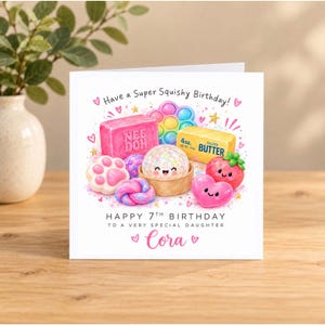 May include: A square birthday greeting card featuring a colorful illustration of squishy toys, a butter stick, and a strawberry with faces. Text reads: Have a Super Squishy Birthday! HAPPY 7TH BIRTHDAY TO A VERY SPECIAL DAUGHTER Cora.