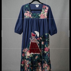 Puede incluir: Un vestido midi azul marino con escote cuadrado, mangas tres cuartos y falda fruncida. El corpiño y el dobladillo tienen un patrón de cuadros verde oscuro y flores rosas. Una aplicación de terciopelo muestra una figura con paraguas.