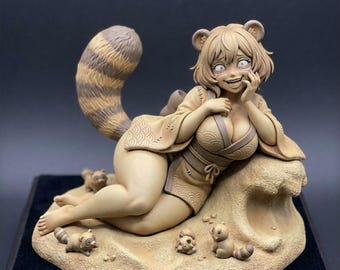 May include: A tan-colored resin figurine of a humanoid character with raccoon ears and a large striped tail, wearing a kimono. The character reclines on a sandy base surrounded by four small raccoon figures, with a sculpted wave-like rock formation.