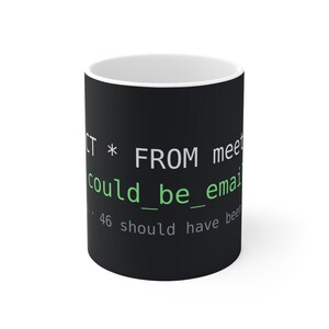 May include: A black ceramic mug with white and light green text that reads SELECT * FROM meetings; could_be_email; 46 should have been. The interior of the mug is white, and the exterior features a computer code-inspired design.