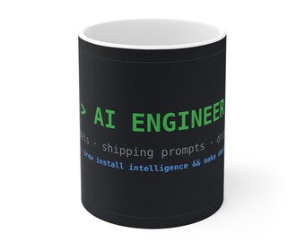 Puede incluir: Una taza de cerámica negra con interior blanco que presenta texto verde que dice AI ENGINEER, seguido de texto gris que dice shipping prompts, y texto azul que dice brew install intelligence && make deploy.