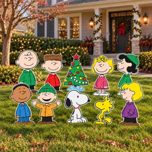 May include: A collection of Peanuts character yard signs featuring Charlie Brown, Snoopy, Woodstock, Lucy, Linus, Sally, and others standing around a decorated Christmas tree. Each cutout displays the iconic cartoon figures in colourful winter clothing.