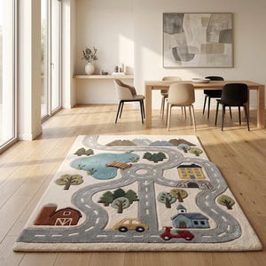 May include: A rectangular area rug featuring a play mat design with a light cream background. The rug displays a gray road network, a blue pond with a wooden bridge, green trees, brown mountains, a red barn, a yellow house, and a blue building.