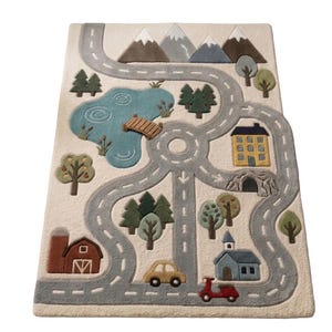 May include: A rectangular area rug with a cream background featuring a tufted landscape design. The scene includes a gray road network, a blue lake with a wooden bridge, brown mountains, green trees, a red barn, a yellow house, a blue building, a yellow car, and a red scooter.