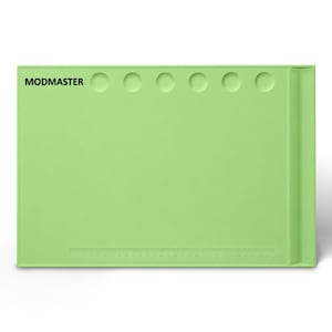 May include: A rectangular light green silicone work mat featuring the text MODMASTER in black, six circular indentations along the top edge, and a printed ruler along the bottom edge that measures up to 30 centimeters in length.