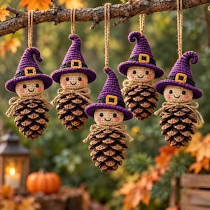 Pode incluir: Cinco ornamentos pendentes com chapéus de bruxa de crochê roxos com fivelas amarelas, usados por pequenas cabeças de crochê bege com bochechas rosadas e rostos sorridentes, presos a corpos de pinha com cordões de juta para pendurar.