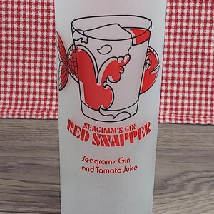 May include: Frosted glass with a red and black graphic of a cocktail, a fish, and the words "Red Snapper" and "Seagram's Gin and Tomato Juice". The glass is cylindrical and has a vintage aesthetic.