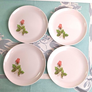 Op de afbeelding: Vier witte keramische borden met een roze roos en groene bladeren ontwerp. De ronde borden hebben een eenvoudige, elegante uitstraling, perfect voor een formele of informele eetsituatie.