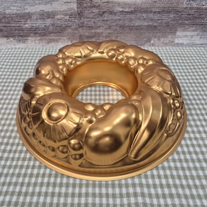 Forma vintage em alumínio cor de cobre com formato de anel e desenho de frutas, ideal para bolos ou gelatinas.