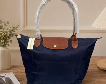 Bolso tote Longchamp azul marino de nailon con ribete de piel marrón, ideal para viajes y uso diario.
