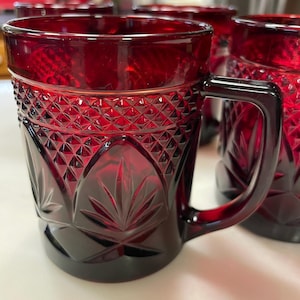 May include: Set of four ruby red glass mugs with a diamond pattern and a leaf design. The mugs have a handle and are perfect for serving beverages.