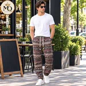 May include: A plain white short-sleeved t-shirt paired with loose-fitting trousers featuring a complex, multi-coloured geometric and elephant pattern. The trousers include a white drawstring waist with decorative beads at the ends and white trainers.
