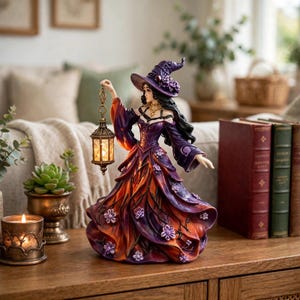 May include: A figurine of a person wearing a purple and orange gown with a matching pointed hat, adorned with small purple flowers. The figure holds a lit, ornate gold-toned lantern. The gown features a layered, flowing design with dark branch-like patterns throughout the fabric.