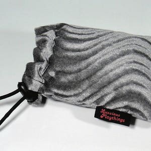 May include: A gray velvet drawstring bag with a black drawstring and a pink label that says "Luscious Playthings".