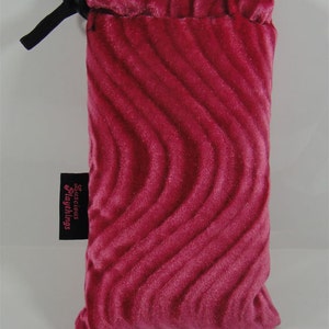 May include: A pink velvet drawstring bag with a black drawstring and the text "Succubus Playthings" on a black tag.