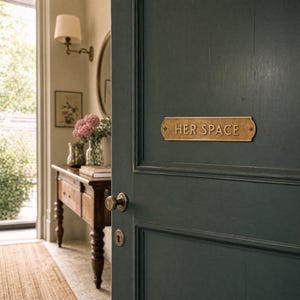 Puede incluir: Una placa de puerta rectangular de lat&oacute;n con acabado desgastado que presenta el texto en relieve HER SPACE, montada en una puerta de paneles verde oscuro con un pomo redondo de lat&oacute;n a juego y una placa de cerradura tradicional.