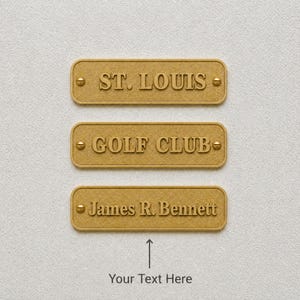 Puede incluir: Tres placas rectangulares de metal dorado con esquinas redondeadas y cabezas de tornillo visibles a cada lado. La placa superior dice ST. LOUIS, la del medio GOLF CLUB y la inferior James R. Bennett. Debajo hay una flecha y el texto Your Text Here.