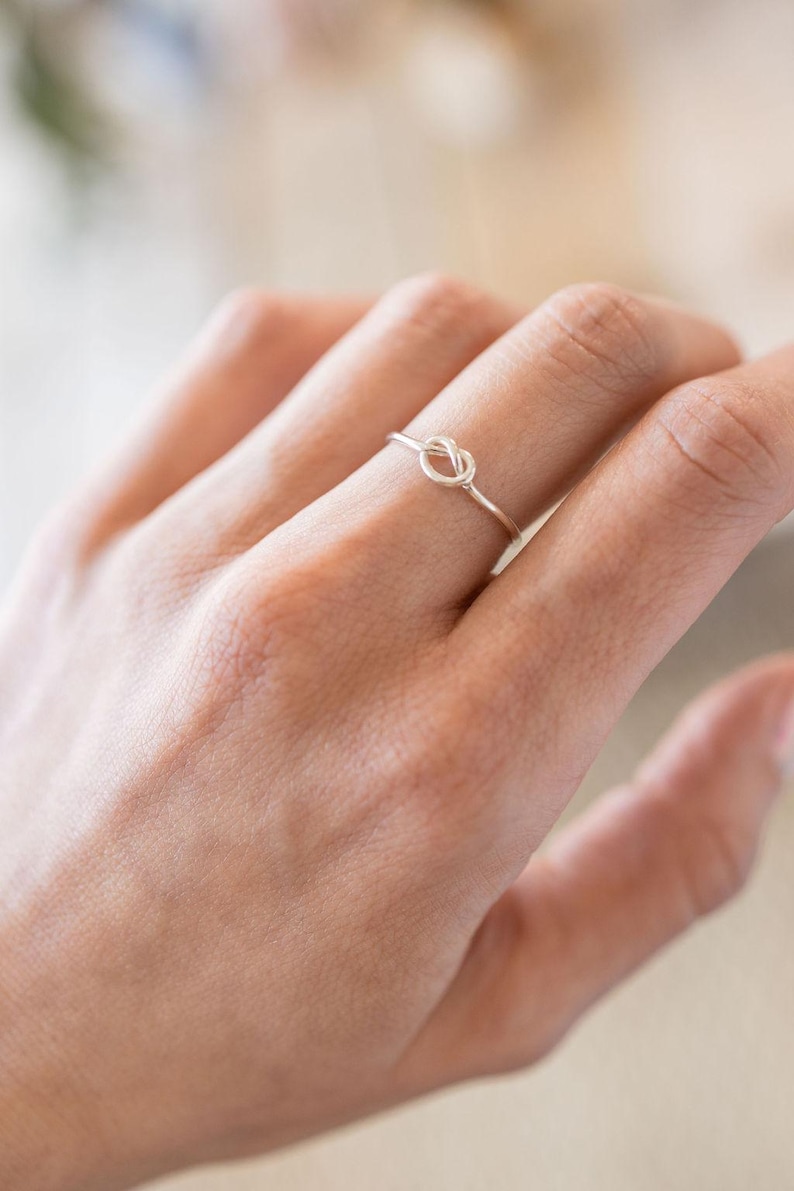 May include: A silver knot ring on a finger.