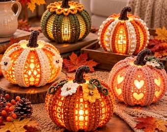 May include: Five crocheted pumpkins in various colours including green, orange, white, and pink, each featuring a dark brown stem and internal warm lighting. The pumpkins are decorated with crocheted flowers, pearls, and heart-shaped cutouts.