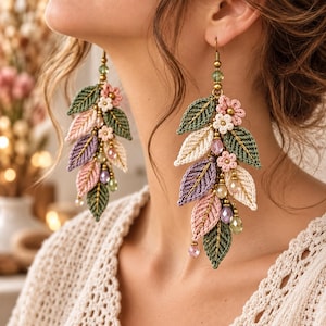Può includere: Orecchini pendenti con un grappolo di foglie all'uncinetto nei toni del verde salvia, rosa antico, crema e lavanda. Il design incorpora piccoli fiori all'uncinetto e perline di cristallo sfaccettato in colori coordinati, appesi a ganci color bronzo.