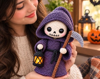 May include: A crocheted grim reaper doll featuring a purple hooded robe, a white skull face with large black eyes, and pink cheeks. The doll holds a brown staff with a grey scythe blade and a small black lantern with a glowing orange light.