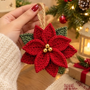 Può includere: Un ornamento a forma di stella di Natale realizzato all'uncinetto con petali rosso vivace e foglie verde scuro. Il centro del fiore è decorato con tre piccole perline dorate lucide. Un cappio in corda di juta naturale è fissato sulla parte superiore.