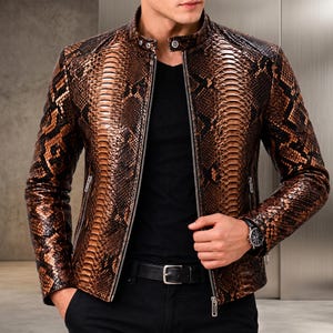 Pode incluir: Uma jaqueta com padrão de pele de cobra em tons de castanho e preto, com gola mandarim, fecho de correr prateado a todo o comprimento e dois bolsos laterais com fecho. A jaqueta é usada sobre uma camisa preta lisa e calças pretas com cinto.