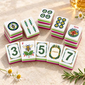Puede incluir: Un juego de fichas de mahjong blancas con ilustraciones coloridas de abejas, flores y números. Las fichas tienen bordes superpuestos verdes y rosas, con algunas mostrando el texto RED, F y JOKER junto a motivos botánicos.