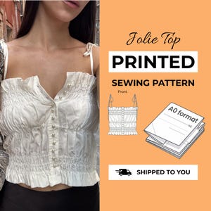 May include: A white Jolie Top sewing pattern featuring a ruched bodice, thin tie straps, and a vertical row of pearl-like buttons. The graphic includes the text Jolie Top PRINTED SEWING PATTERN, a line drawing of the front, and an A0 format paper stack.