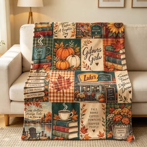 May include: A rectangular throw blanket featuring a patchwork design with autumn-themed illustrations including pumpkins, stacks of books, coffee mugs, maple leaves, sunflowers, and a diner storefront with the text Luke's and Stars Hollow.
