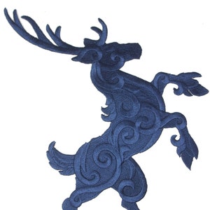 May include: A navy blue embroidered patch depicting a stylized stag in a leaping pose. The stag's form is intricately detailed with swirling patterns, creating a textured appearance. The patch is designed for application on fabric.