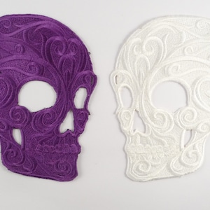 May include: Two embroidered skull patches, one purple and one white, with intricate floral designs.