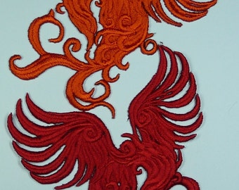 Pode incluir: Dois fénix bordados, um vermelho e outro laranja, com detalhes intrincados e padrões em espiral. Os fénix estão de frente um para o outro com as asas abertas.