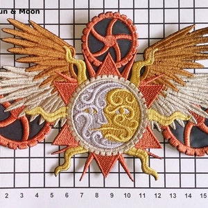 May include: Embroidered patch with a sun and moon design. The sun and moon are surrounded by gears and wings. The patch is orange, yellow, white, and gray.