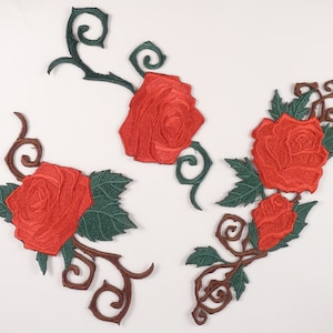 May include: Three red embroidered rose patches with green leaves and brown vines. The roses are in a traditional style with a swirl design.