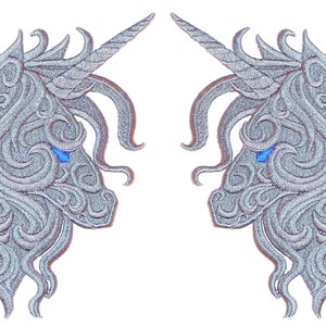 May include: Two silver embroidered unicorn heads with blue eyes, facing each other.
