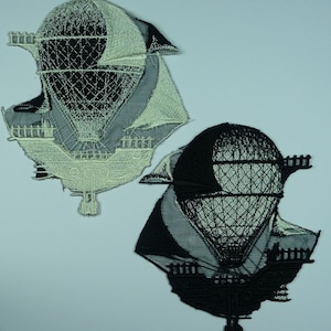May include: Two embroidered patches of a hot air balloon with a basket. One patch is white and the other is black.