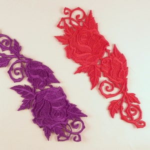 May include: Two embroidered rose appliques, one in purple and one in red, with intricate floral designs and swirling vines.