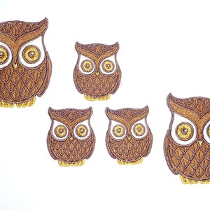 Könnte beinhalten: Satz mit vier braunen gestickten Eulen-Patches mit gelben Akzenten und weißen Augen. Die Eulen sind in verschiedenen Größen.