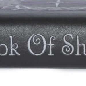May include: A black leather-bound book with the words "Book of Shadows" embossed in silver lettering.